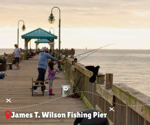 Father and daughter fish from pier after sunrise. 