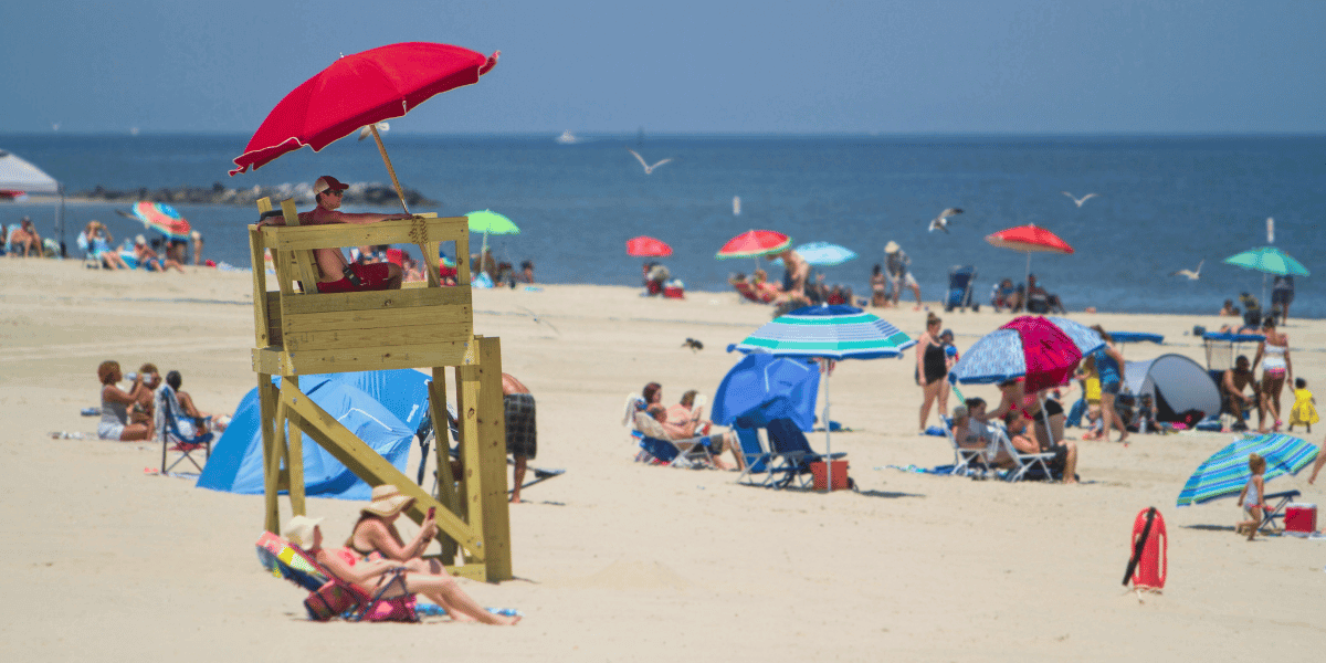 Beachgoers enjoy a sunny day under a sea of colorful umbrellas near a lifeguard at Buckroe Beach in Hampton, VA. 