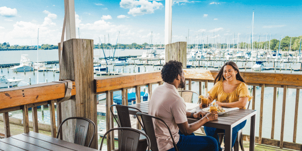 Couple dines at The Deadrise in Hampton with scenic view of boats in harbor in the background