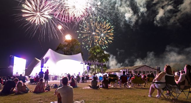 Groups of people watch a fireworks show.