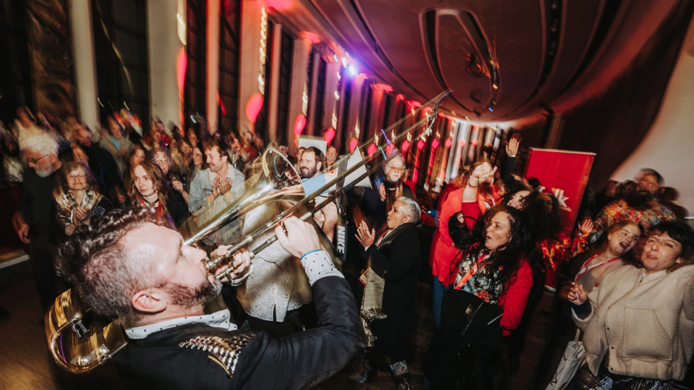 Trombone player plays in crowd of dancing and singing people