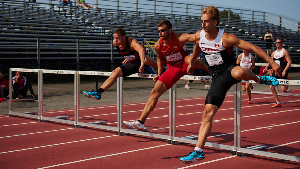 Three men compete in hurdles